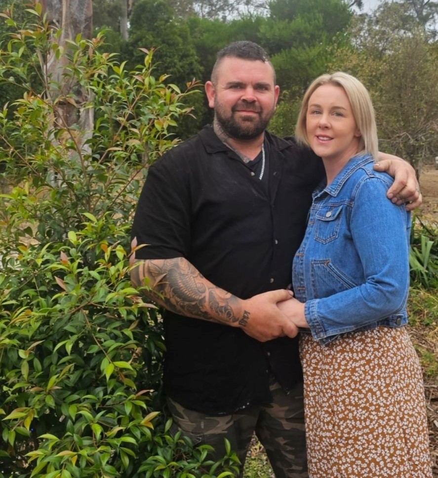 A photo of Belinda and Callum standing outside and holding hands,